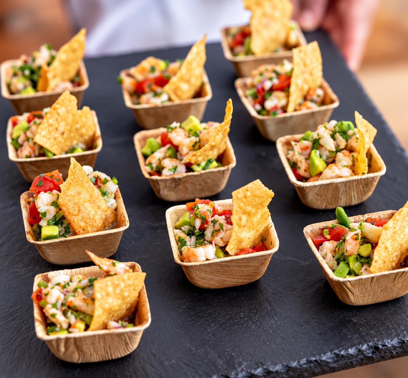 Ceviche cups with tortilla chips on a black serving tray