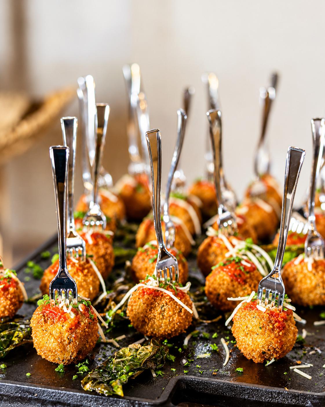 Crispy croquettes served on mini forks over a black slate