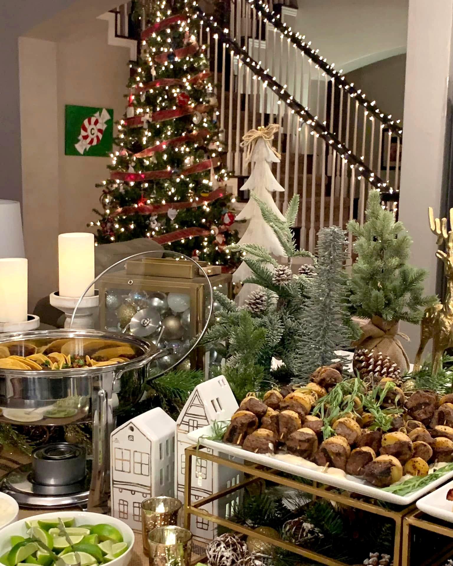A Knife & Faulk holiday buffet with candles, evergreens and a lit Christmas tree